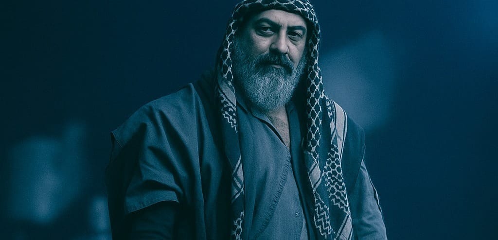 Man in robes under blue light.