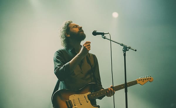 man with electric guitar standing on stage