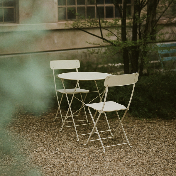 a couple of white folding chairs and a white tablesitting on top of a gravel field