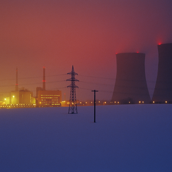 a snowy field with power lines and nuclearpower plant in the background